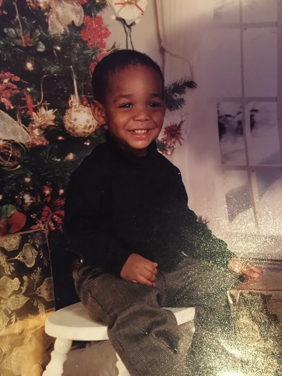 Jerry Fort as a child indoors beside a Christmas tree.